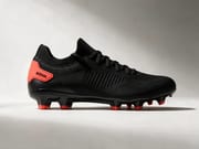 Black football boot with orange-red studs