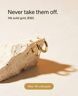 Product hero shot: gold hoop earrings on travertine