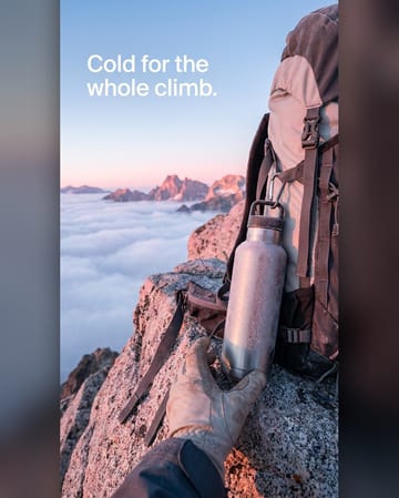 Lifestyle product photo: an insulated bottle on a backpack at sunrise
