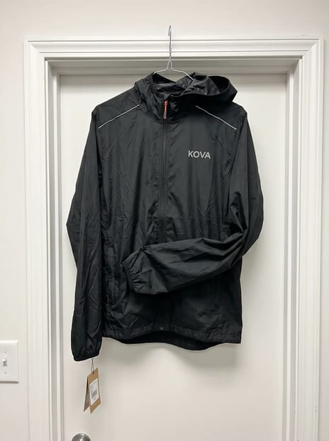 Phone photo of a black running jacket on a wire hanger