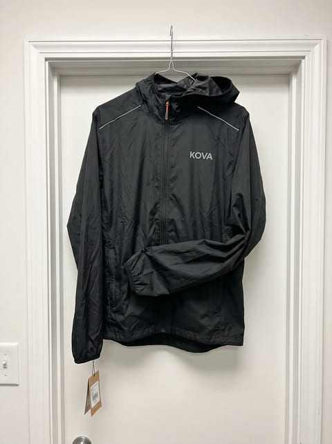 Phone photo of a black running jacket on a wire hanger