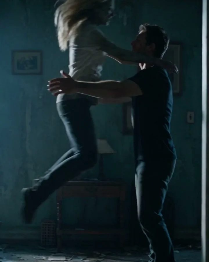 Two people embracing in a dark room in a post-apocalyptic scene